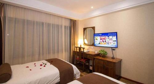 a hotel room with two beds and a desk and a television at James Joyce Coffetel Xian Dayanta Metro Station Branch in Xi'an