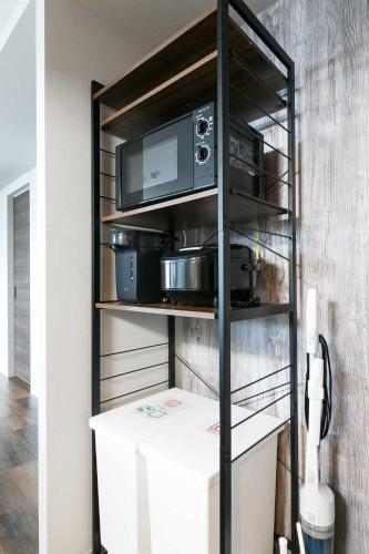 a black shelf with a microwave and some pots and pans at Twinberry CHITOSE in Chitose