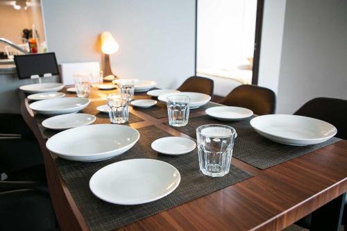 a wooden table with white plates and glasses on it at Twinberry CHITOSE in Chitose