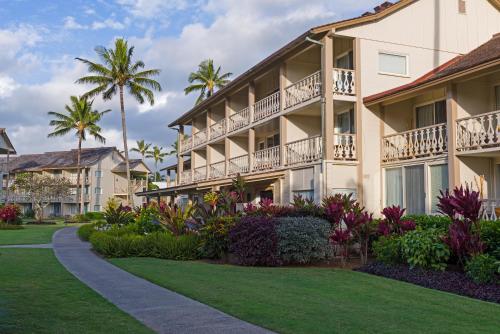 a resort building with a lawn and palm trees at Aston Islander On The Beach in Kapaa