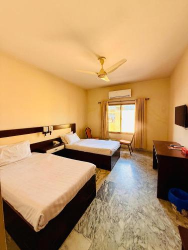 a hotel room with two beds and a window at Pameer Hotel Mingora in Mingora