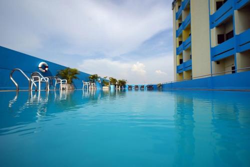 a swimming pool with chairs in the water next to a building at Riverside Bangkok Hotel in Bangkok