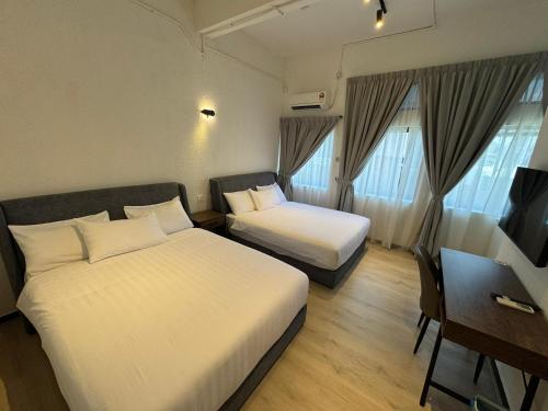 a hotel room with two beds and a desk at Robin Hotel in Ipoh