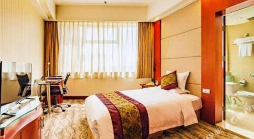 a hotel room with a bed and a desk at Junyu Grand Hotel Qinhuangdao in Qinhuangdao