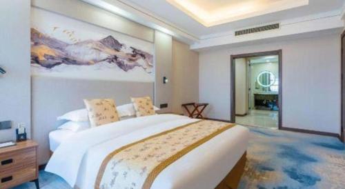 a bedroom with a large bed with a painting on the wall at Junyu Grand Hotel Qinhuangdao in Qinhuangdao