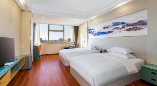 a hotel room with two beds and a flat screen tv at Junyu Grand Hotel Qinhuangdao in Qinhuangdao