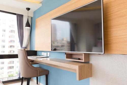 a tv on a wall with a desk and a chair at 衿后禾居民生館 Good Hotel Minsheng in Kaohsiung