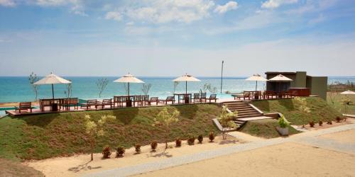 a resort with tables and umbrellas on the beach at Laya Safari Resorts & Spa in Yala