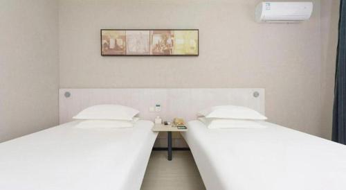 two twin beds in a room with a table at Jinjiang Inn Dalian Development Zone Jinma Road Light Railway Station in Jinzhou