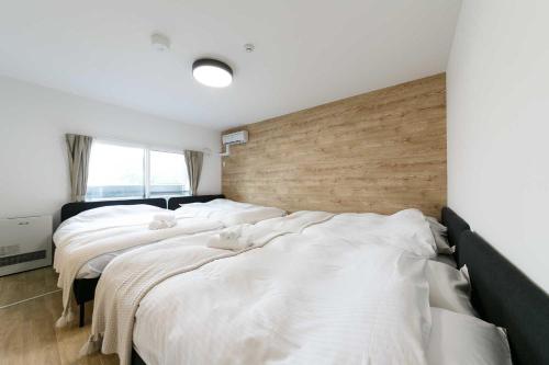 three beds in a room with white sheets at EFFECT minami7 in Sapporo