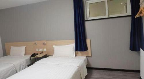 two beds in a room with blue curtains at 7 Days Inn Tianjin Binhai New District Yujiabao Metro Station in Binhai