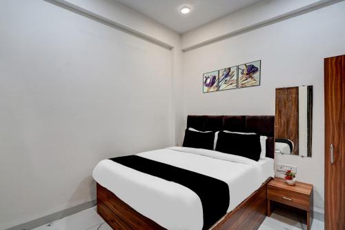 a bedroom with a bed with white and black sheets at Hotel O Mannat in Indore