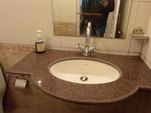 a sink in a bathroom with a person taking a picture at Hotel Aroma Nainital In house parking in Nainital
