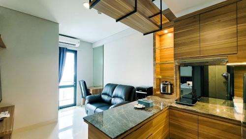 a living room with a leather chair and a kitchen at Palam Mansion at Apartment One Residence in Batam Center