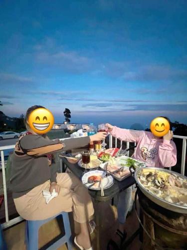 two people dressed as faces sitting at a table with food at สเตชั่นภูทับเบิก-บ้านดาดฟ้าทะเลหมอก in Ban Tha Kok Hai