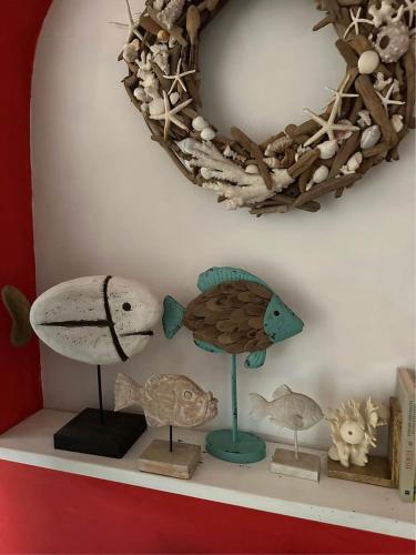 a shelf with several figurines of fishes and a wreath at La Casa di SASI in Sabaudia