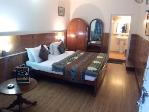 a bedroom with a bed and a table in a room at Hotel Aroma Nainital In house parking in Nainital