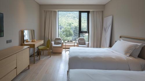 um quarto de hotel com uma cama, uma secretária e uma janela em The Nook Hotel Hangzhou - A design hotel, Near subway em Hangzhou