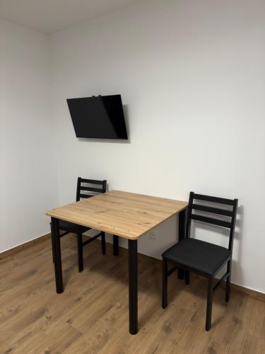 a wooden table with two chairs and a tv on a wall at Domki i Apartamenty Pod Wzgórzem in Polańczyk