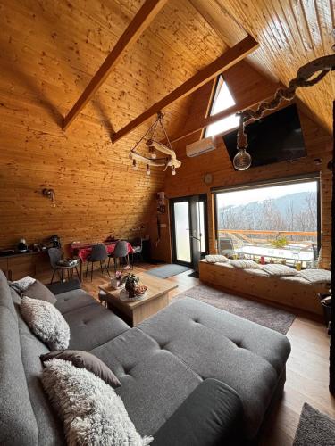 a living room with a couch and a large window at Cabana Lupul din Apuseni in Mătişeşti
