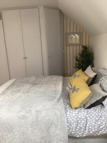 1 dormitorio con 1 cama con almohadas amarillas y grises en Lovely Bed and Breakfast in Chichester nr Festival Theatre City Centre and Goodwood Top Floor Spacious Kingsize Ensuite, en Lavant