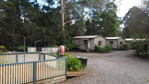 a house in a yard with a fence and a gate at Strahan Retreat Holiday Park in Strahan