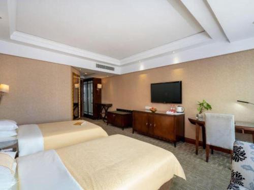 a hotel room with two beds and a flat screen tv at Chinflux Mandarin Hotel in Dongguan