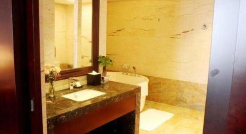 a bathroom with a sink and a mirror and a tub at Weida Hotel Jinhua in Jinhua