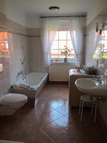 uma casa de banho com uma banheira, um WC e um lavatório. em Hotel Heidetraum em Schneverdingen