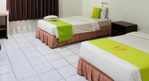 a hotel room with two beds with green and white at Hotel Huswah Airport in Jakarta