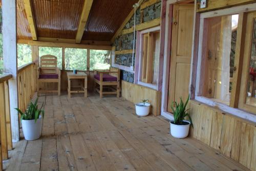 a screened porch of a house with potted plants at Mysterious Kutla Cottage,Kutla, Tosh in Chhorang