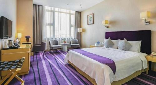 a hotel room with a large bed and a tv at The Bauhinia in Shenzhen