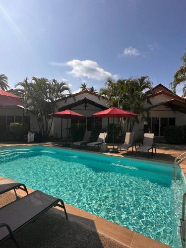 a large swimming pool with chairs and umbrellas at Vivi Bungalows Resort in Nai Harn Beach