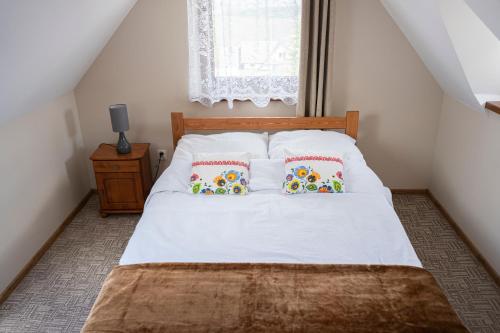 a bedroom with a bed with two pillows and a window at Noclegi Olszówka in Bukowina Tatrzańska