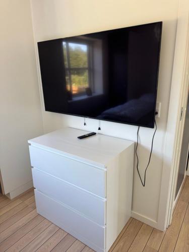 a flat screen tv on top of a white dresser at Bøtø strand ferielejlighed 1 in Marielyst
