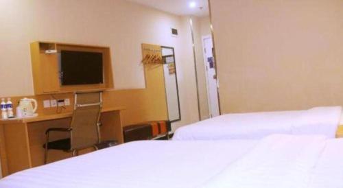a hotel room with two beds and a desk and a television at 7 Days Premium·Xiamen Airport Xianglu in Xiamen