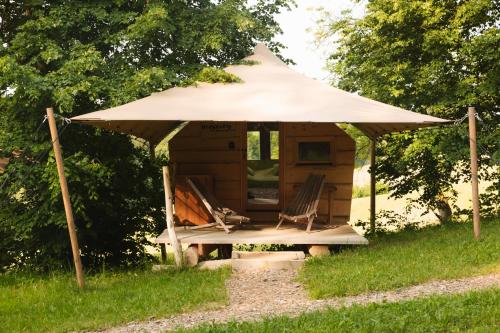 a gazebo with two chairs and an umbrella at Lakeside Glamping Tents Mažijev Grič in Gradišče pri Lukovici