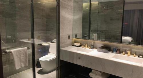 a bathroom with a toilet and a sink and a mirror at Taiyi International Hotel in Wenzhou