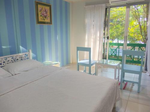 a bedroom with a bed and two chairs and a balcony at Makmai Villa - Rayong in Ban Phe