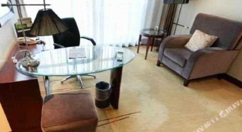 a living room with a glass table and a chair at Gaosu New Century Hotel International Anhui in Hefei