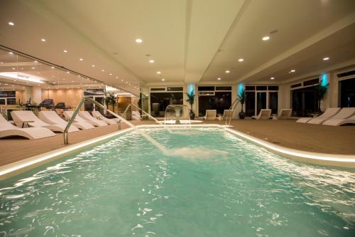 a large swimming pool in a hotel with white chairs at ON Hotels Oceanfront Adults Designed in Matalascañas