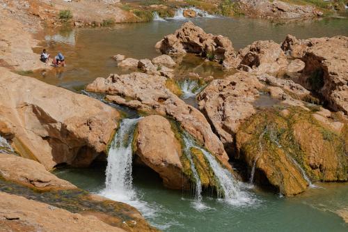 two people standing in a river with two waterfalls at Kasbah Tissint in Tissint