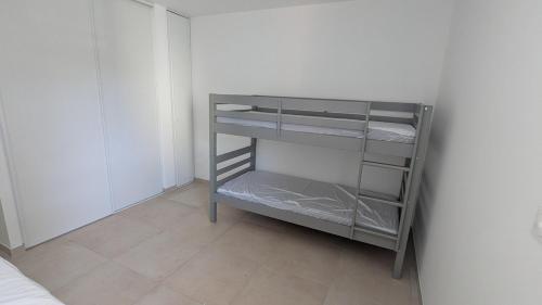une petite étagère grise dans une pièce blanche dans l'établissement appartement neuf en centre-ville, à Cavalaire-sur-Mer