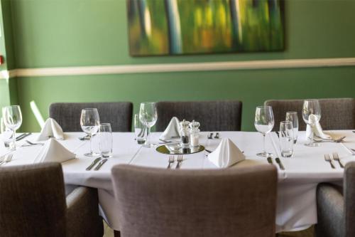 a dining room with a table with glasses and chairs at DoubleTree by Hilton Cheltenham-Cotswolds in Cheltenham