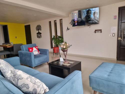a living room with two blue couches and a table at Hostal K & A in Zacatlán