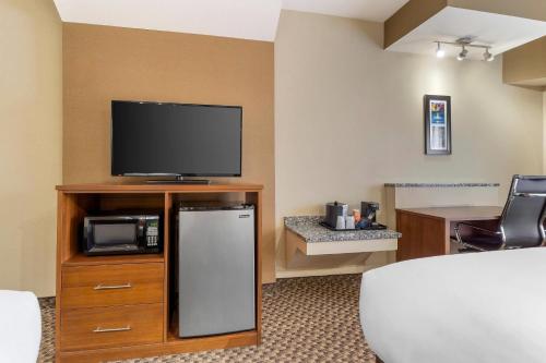 a hotel room with a tv and a refrigerator at Comfort Suites Monroeville - Pittsburgh East in Monroeville