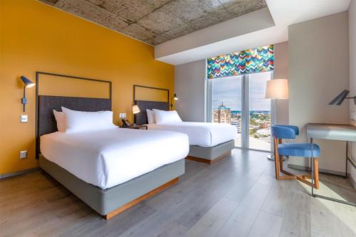 a hotel room with two beds and a desk and a window at Tru By Hilton Chillan Ferrat in Chillán