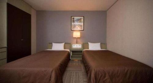 a room with two beds and a table with a lamp at New Biwako Hotel in Otsu