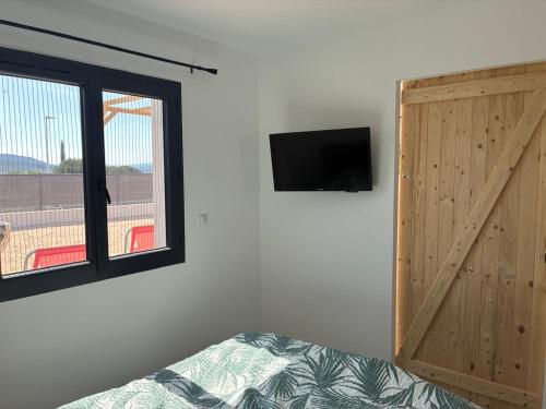 une chambre avec une porte coulissante et une télévision au mur dans l'établissement villa de vacances, à Cessenon