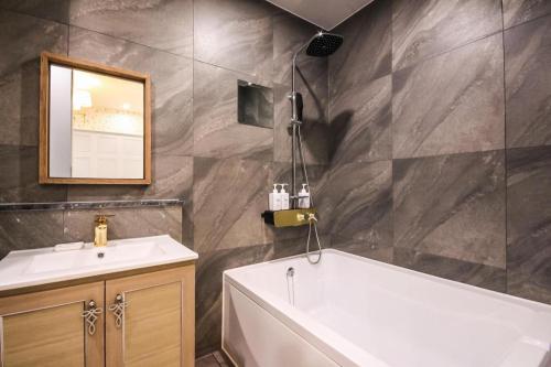 a bathroom with a tub and a sink and a mirror at Hotel Seowa in Gimhae